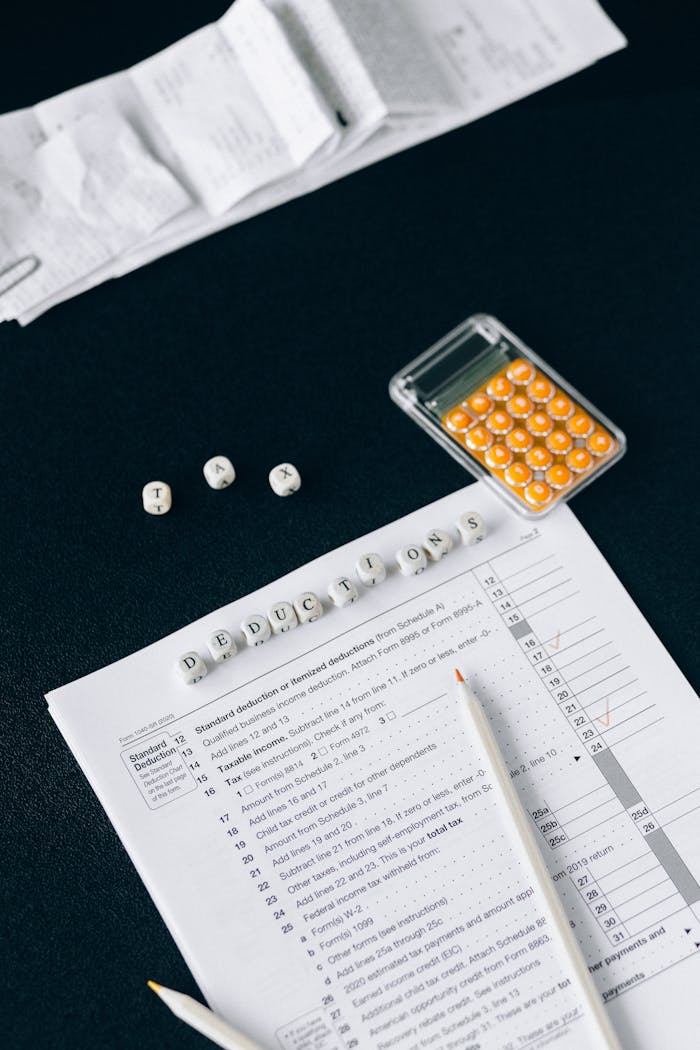 Flat lay of tax documents, calculator, and labeled deductions on a black background.