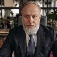 Portrait of a senior businessman with a gray beard in an office environment.